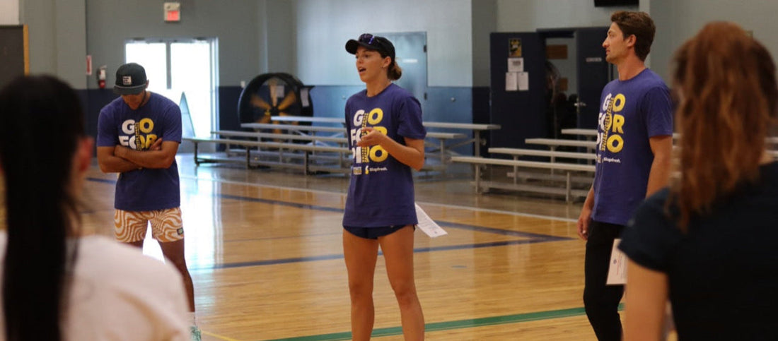 Adult coach in USSPT gear teaching volleyball techniques, with athletes training in a gym setting